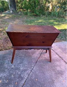 an old wooden chest sitting on top of a cement floor in front of trees and grass