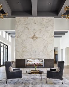 a living room with two chairs and a coffee table in front of a large fireplace