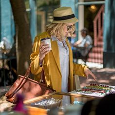 a woman in a yellow coat and hat looking at her cell phone