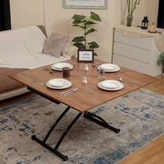 a table with plates and silverware on it in front of a couch next to a coffee table