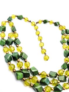 Vintage Christmas Holiday three tiered Green and gold plastic beaded bib necklace. Beautful iconic vintage beaded necklace. This unique piece has alternating Hunter green and faceted light green beads with gold accents. Adjustable length. Good vintage condition with small signs of normal vintage wear. Necklace measures approx. 13 - 19 inches Retro Green Beaded Necklace For Gift, Green Faceted Beads Necklace For Costume Jewelry, Green Faceted Beaded Necklace For Costume Jewelry, Festive Green Vintage Jewelry, Retro Green Beaded Necklaces, Vintage Adjustable Green Beaded Necklaces, Vintage Green Jewelry With Faceted Beads, Green Faceted Beads Costume Jewelry Necklace, Green Faceted Beads Costume Necklace