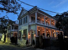 a large white house sitting on the side of a road at night with lights on