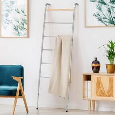 a ladder leaning up against a wall next to a blue chair and potted plant