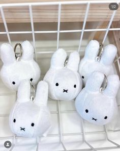 several white stuffed animals are on display in a wire rack with key chains attached to them