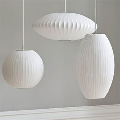 three white lamps hanging from the ceiling in a room with gray walls and flooring