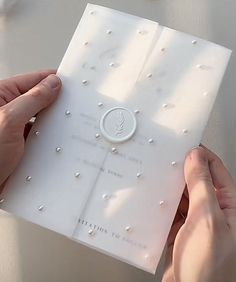 two hands are holding a card with pearls on it