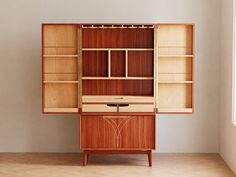 a wooden cabinet with shelves and drawers in an empty room