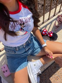 a woman sitting on the ground next to some minnie mouse shoes and mickey mouse ears