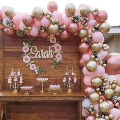 a table topped with lots of pink and gold balloons next to a sign that says safari