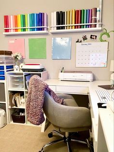 a desk with a chair, computer and many colored papers on the wall above it