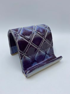 a purple and white ceramic object sitting on top of a table