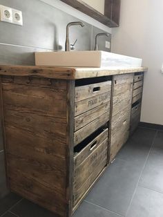 a sink and some drawers in a small room with tile flooring on the walls