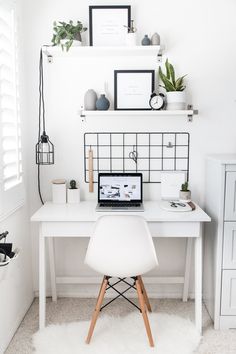 a white desk topped with a laptop computer next to a shelf filled with potted plants