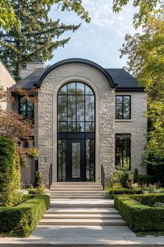 the front entrance to a modern home surrounded by hedges