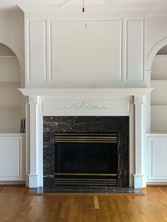 an empty living room with a fireplace and white walls