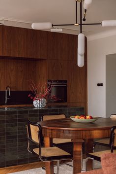 a bowl of fruit sits on a table in the middle of a room with chairs