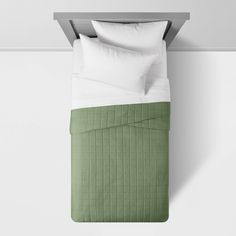 a bed with white pillows and green bedspread