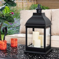 an outdoor table with candles on it in front of a couch and some chairs outside