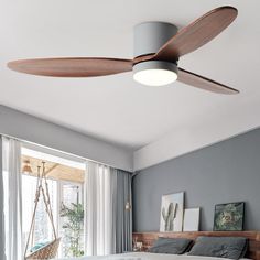 a bedroom with a bed, ceiling fan and window in the corner next to it