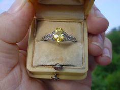 Here is a beautiful antique platinum ring.  It holds a yellow sapphire center with tiny single cut diamonds down the sides of the band.  The setting is marked with a serial number but the platinum content has worn off.  It has been tested to be 88% platinum.  The diamonds are SI to I clarity with one diamond chipped.  The sapphire has some facet abrasion and a small girdle chip seen under magnification. The finger size is about 6.5 on my mandrel. This is a lovely, petite and feminine Edwardian period ring. The ring box shown is my display.  I will ship in a different vintage box or you may request a new box. Yellow Heirloom Ring For Collectors, Yellow Heirloom Ring, Yellow Heirloom Collectible Ring, Heirloom Yellow Topaz Wedding Ring, Antique Yellow Rings For Anniversary, Yellow Sapphire Ring With Brilliant Cut For Wedding, Yellow Brilliant Cut Sapphire Wedding Ring, Wedding Yellow Sapphire Ring With Brilliant Cut, Antique Yellow Rings For Collectors