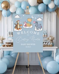 a welcome sign for a baby shower with blue balloons and pooh bear decorations in the background