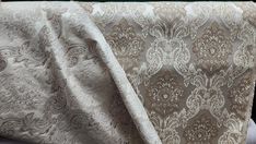 a white and beige fabric with an intricate design on the side, draped over a chair