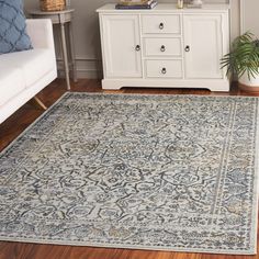 a living room with white furniture and blue rug