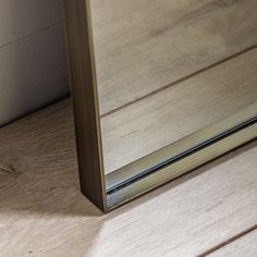 a mirror sitting on top of a wooden floor next to a white wall and door