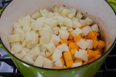 chopped potatoes and carrots in a green pot on the stove top with other vegetables