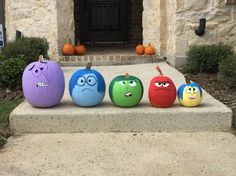 four pumpkins with faces painted on them sitting in front of a door and steps