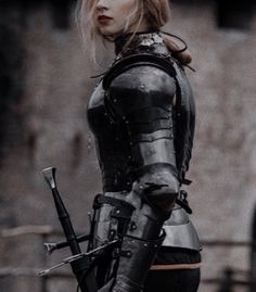 a woman dressed in armor holding two swords and looking off into the distance with her hand on her hip