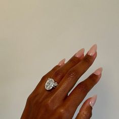 a woman's hand with a diamond ring on her left hand, against a white background