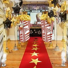 a red carpet with gold stars on it and some black and white balloons in the background