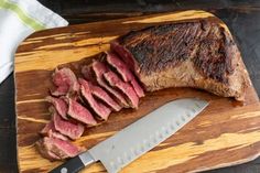 the steak is cut up and ready to be served on the cutting board with a knife