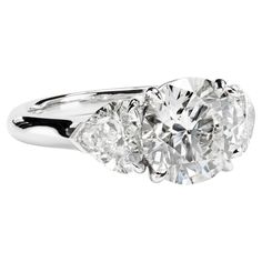 a three stone diamond ring with two diamonds on the band and an oval brilliant setting