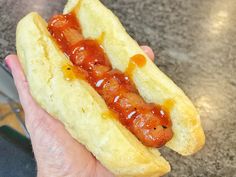 a person holding a hot dog with ketchup on it