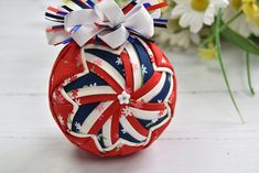 a red, white and blue ornament sitting on top of a table next to flowers