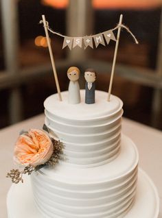 a wedding cake with two figurines on top and bunting banner above it