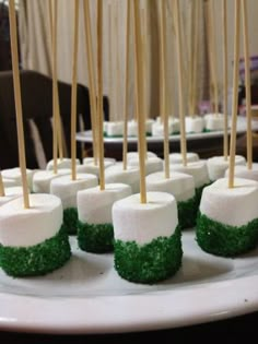 marshmallows with green grass and wooden skewers on a white plate