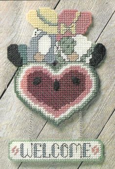 there is a cross stitch pattern on the back of a heart shaped sign that says welcome