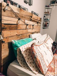 a bed made out of pallets with pillows and blankets on top of the headboard