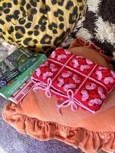 there is a pillow and some books on the bed with leopard print pillows behind it