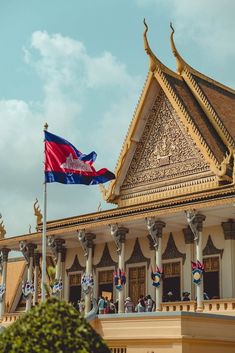 a flag flying in front of a building with ornate designs on the roof and sides