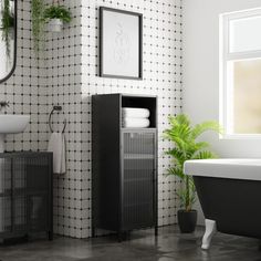 a bathroom with black and white tiles on the wall next to a bathtub, sink and mirror