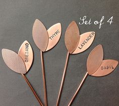 four metal spoons with words on them sitting next to each other in front of a gray background