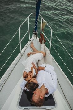 a man and woman are laying on the back of a boat in the water with their arms around each other