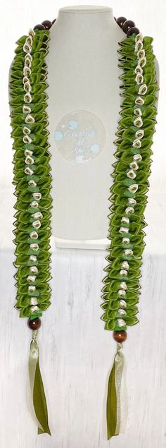 a green and white necklace is hanging on a mannequin