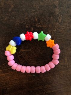 several different colored bracelets on a wooden table with one bead in the shape of a star