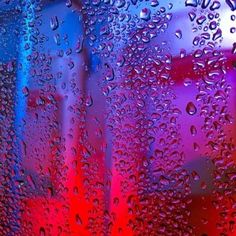 rain drops on the window with red and blue lights in the backgroung