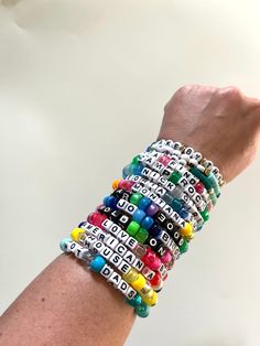 a woman's arm with several bracelets made out of beads and letters on it